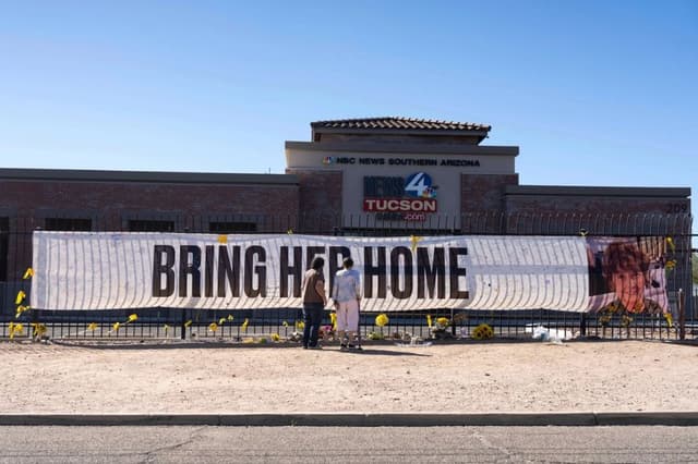 Varias personas visitan una pancarta en memoria de Nancy Guthrie, la madre desaparecida de Savannah Guthrie, presentadora del programa "Today", frente a la redacción de KVOA en Tucson, Arizona, el 6 de marzo de 2026. (Foto AP/Rebecca Noble)