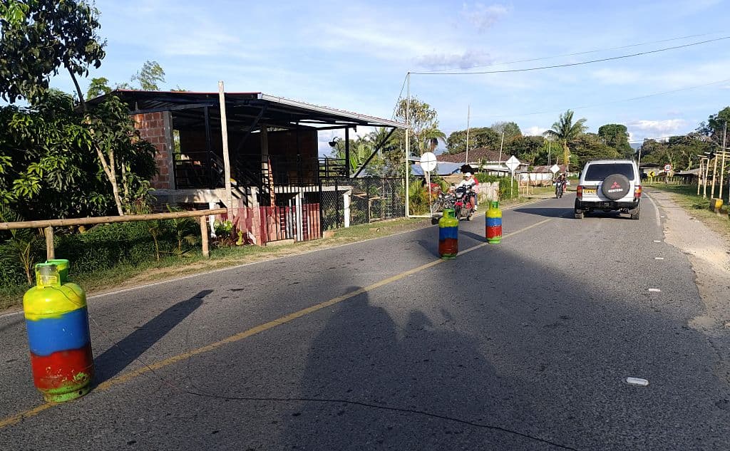 Vehículos pasan junto a cilindros que, según se afirma, fueron colocados por disidentes de las FARC en la carretera, en el departamento del Cauca, Colombia, el 14 de septiembre de 2025. (PEDRO MORALES/AFP vía Getty Images)