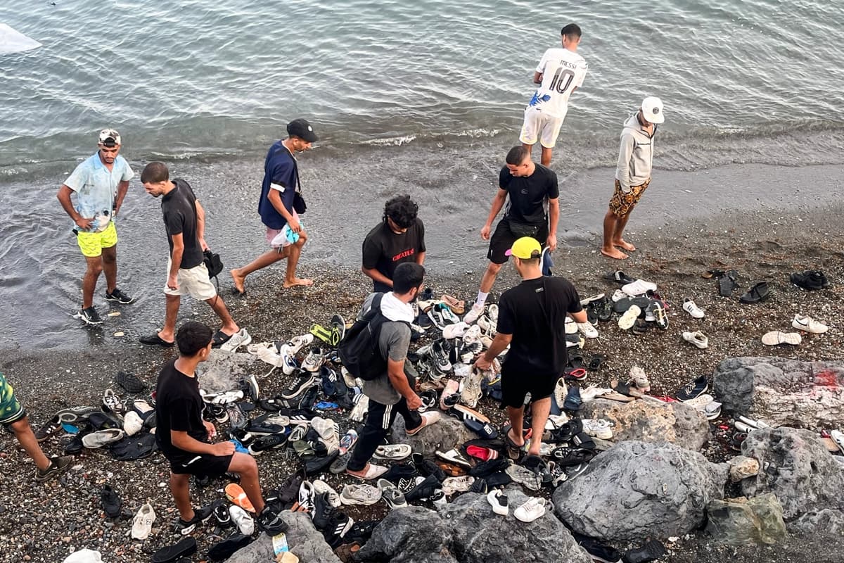 Jóvenes inmigrantes marroquíes revisan montones de zapatos desechados tras nadar desde Marruecos en una playa rocosa cerca de la Avenida Martínez Catena, en el territorio español de Ceuta, el 31 de julio de 2026. (Etienne Fauchaire para The Epoch Times).