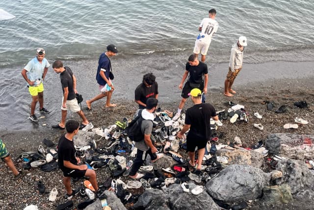 Jóvenes inmigrantes marroquíes revisan montones de zapatos desechados tras nadar desde Marruecos en una playa rocosa cerca de la Avenida Martínez Catena, en el territorio español de Ceuta, el 31 de julio de 2026. (Etienne Fauchaire para The Epoch Times).
