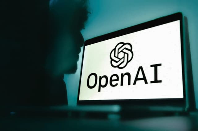 Un ordenador con el logotipo de OpenAI se monta sobre un fondo azul degradado con la sombra de un hombre en el fondo en Grenoble, Francia, el 12 de febrero de 2025. (Anouk Anglade/Hans Lucas/AFP vía Getty Images).