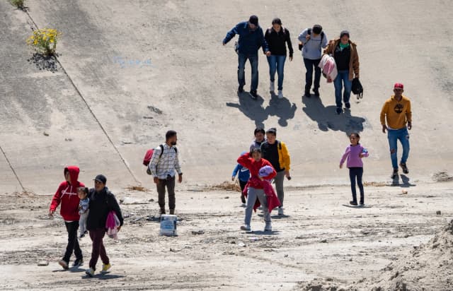 Personas cruzan el río Tijuana y se dirigen hacia el muro fronterizo con Estados Unidos en Tijuana, México, el 11 de mayo de 2023. (John Fredricks/The Epoch Times).