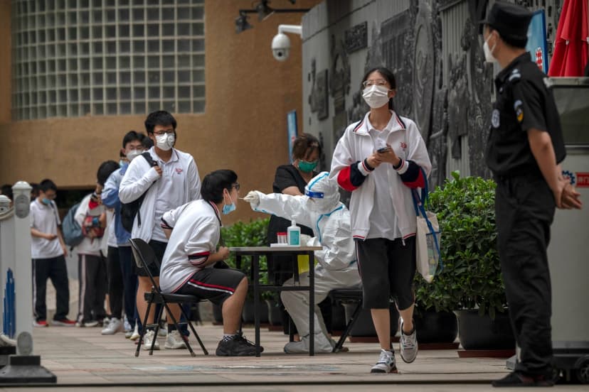 Un trabajador sanitario con traje protector realiza una prueba de ácido nucleico para detectar la COVID-19 a un estudiante tras finalizar el último día del Examen Nacional de Ingreso a la Universidad, también conocido como Gaokao, en un instituto de Beijing el 10 de junio de 2022. (Kevin Frayer/Getty Images).