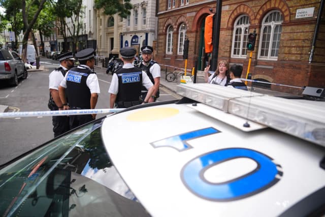Agentes de policía permanecen en el lugar de los hechos en Endell Street, en Covent Garden, tras el apuñalamiento de cuatro hombres en el centro de Londres el 5 de agosto de 2026. (James Manning/PA vía AP).