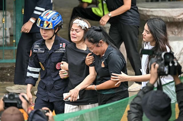 Los familiares de una maestra que perdió la vida en un tiroteo en una escuela son acompañados hasta una ambulancia en el distrito de Bang Kruai, provincia de Nonthaburi, al norte de Bangkok, la capital de Tailandia, el 7 de agosto de 2026. (Lillian Suwanrumpa/AFP vía Getty Images).