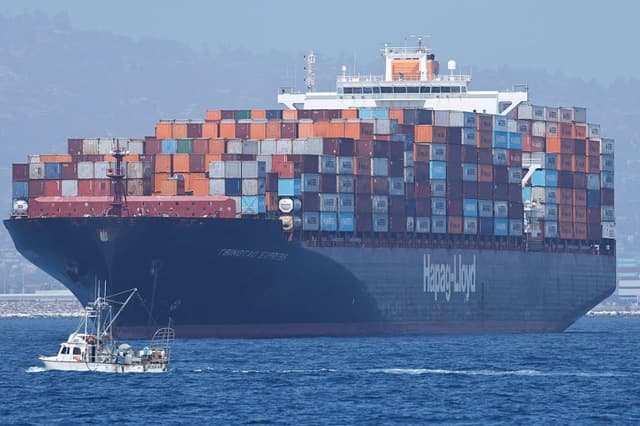 Un barco pesquero pasa junto a un buque portacontenedores que se encuentra a flote frente al puerto de Los Ángeles el 17 de julio de 2026 en Los Ángeles, California. La administración de Trump ha reembolsado 81,000 millones de dólares en aranceles a importadores y transportistas a raíz de un fallo de la Corte Suprema sobre los aranceles generalizados impuestos por la administración. (Mario Tama/Getty Images)