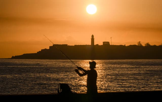 Silueta de un pescador con el faro del Morro al fondo durante un apagón al amanecer en La Habana, el 29 de junio de 2026. (Yamil Lage/AFP vía Getty Images)