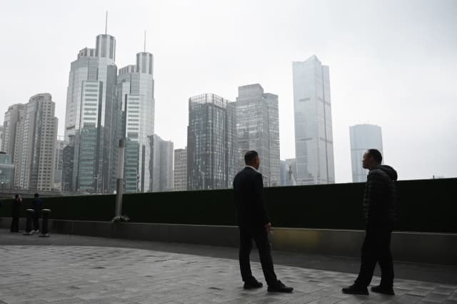 Dos hombres conversan frente a edificios de oficinas en el distrito financiero central de Beijing el 4 de marzo de 2026. (Greg Baker/AFP vía Getty Images).