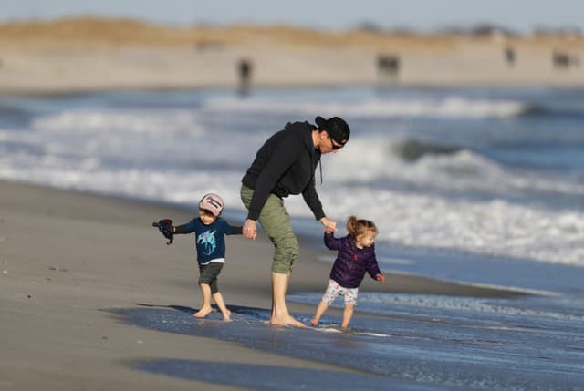Imagen ilustrativa: Un padre jugando con sus dos hijos en la playal (Al Bello/Getty Images)
