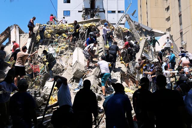 La gente busca sobrevivientes entre los escombros de un edificio derrumbado tras un terremoto en Cali, Colombia, el 10 de agosto de 2026. (Joaquín SARMIENTO / AFP vía Getty Images)