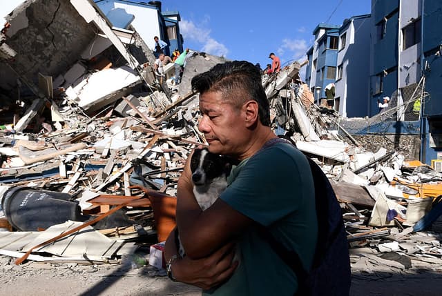 Un hombre lleva un perro mientras camina entre los escombros de un edificio derrumbado tras el terremoto en Pereira, Colombia, el 10 de agosto de 2026. Un potente sismo sacudió Colombia y países latinoamericanos vecinos el 10 de agosto de 2026, (Foto de Jaime SALDARRIAGA / AFP vía Getty Images)