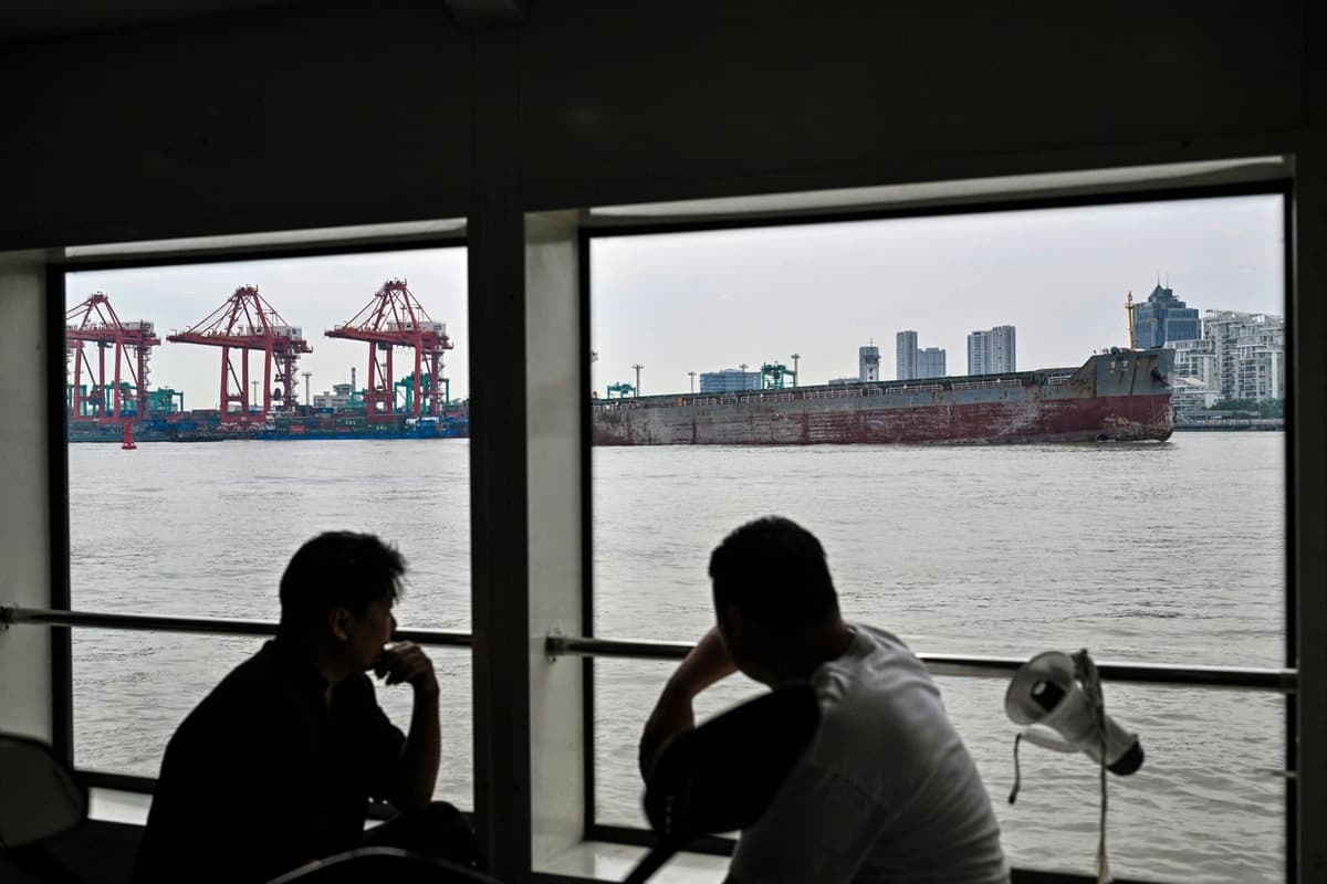 Varias personas se sientan en un ferry que cruza el río Huangpu junto a grúas en las terminales de contenedores de Shanghái, en el muelle de Zhanghuabang, Shanghái, China, el 7 de mayo de 2026. (Hector Retamal / AFP vía Getty Images).