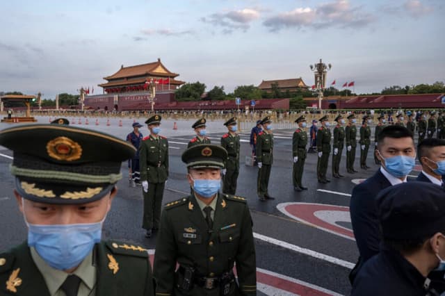Agentes de policía y personal de seguridad controlan a la multitud tras una ceremonia oficial de izamiento de bandera cerca de la Plaza de Tiananmén y la Ciudad Prohibida en Beijing, el 1 de octubre de 2021. (Kevin Frayer/Getty Images).