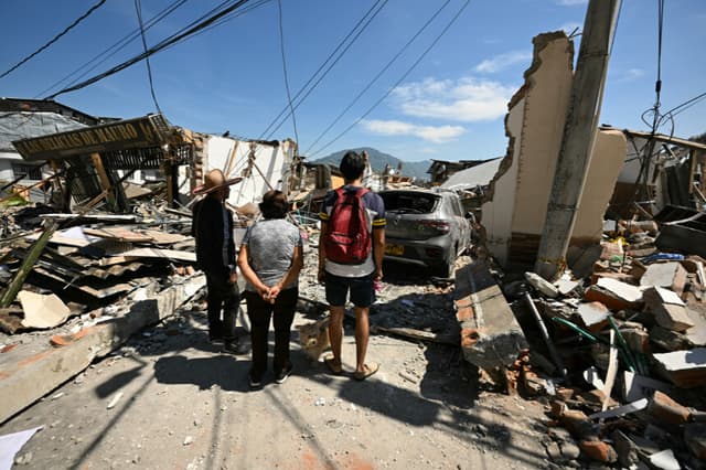 La gente observa una casa derrumbada tras un terremoto en Pereira, Colombia, el 11 de agosto de 2026. Voluntarios y equipos de rescate colombianos retiraron los escombros con sus propias manos para buscar sobrevivientes en la madrugada del 11 de agosto, después de que el terremoto más fuerte que ha sufrido el país en una década dejara al menos 169 muertos y destruyera decenas de edificios. (Luis ACOSTA / AFP vía Getty Images)