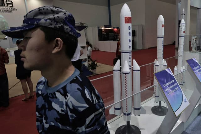 Un guardia de seguridad se encuentra junto a modelos de cohetes chinos expuestos en el 64º Congreso Internacional de Astronáutica en Pekín el 24 de septiembre de 2013. (Mark Ralston/AFP/Getty Images).