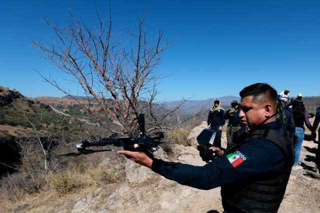 Un agente de la Policía Municipal de Zapopan hace volar un dron sobre la zona donde miembros del colectivo "Guerreros Buscadores" encontraron restos humanos durante la búsqueda de sus familiares en un barranco conocido como "El Potrero", en Zapopan, estado de Jalisco, México, el 26 de noviembre de 2024. (ULISES RUIZ/AFP vía Getty Images)