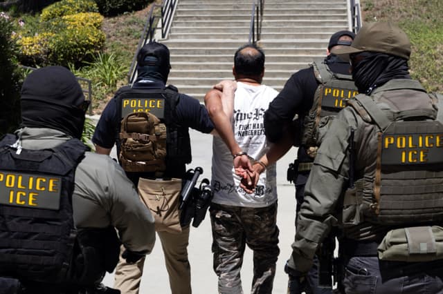 Agentes del Servicio de Inmigración y Control de Aduanas (ICE) escoltan a un detenido al salir del Centro de Gobierno del Condado de Ventura, en Ventura, California, el 27 de julio de 2026. (Blake Fagan / AFP vía Getty Images)