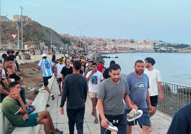 Migrantes marroquíes se congregan para caminar por la carretera costera cerca de la Avenida Martínez Catena en el territorio español de Ceuta, España, el 31 de julio de 2026. (Etienne Fauchaire/The Epoch Times)