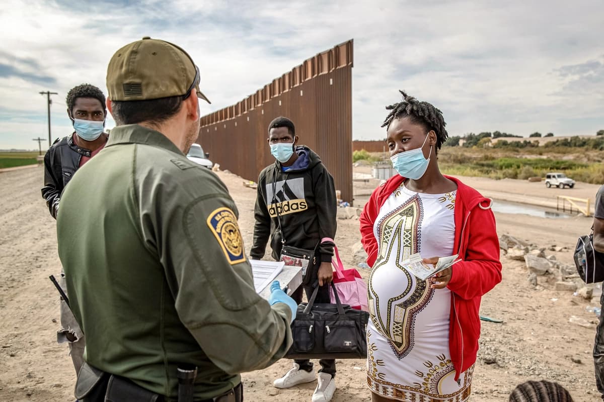 Un agente de la Patrulla Fronteriza de EE. UU. detiene a migrantes, entre ellos una mujer haitiana embarazada que buscaba dar a luz en Estados Unidos, en Yuma, Arizona, el 7 de diciembre de 2021. (John Moore/Getty Images)