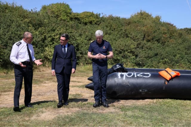 El primer ministro británico, Andy Burnham (C), conversa con John Craig, jefe interino de la Guardia Costera, y Duncan Capps, comandante de seguridad fronteriza (I), junto a una embarcación usada por migrantes para cruzar el Canal de la Mancha, durante una visita a un centro de rescate marítimo en Dover, Inglaterra, el 2 de agosto de 2026. (Jack Taylor/Pool vía AP).