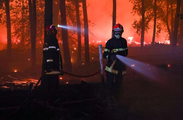 Los bomberos luchan contra las llamas mientras un incendio forestal arrasa el bosque de las Landas en Luglon, al suroeste de Francia, en la madrugada del 14 de agosto de 2026. (Romain Perrocheau/AFP vía Getty Images).