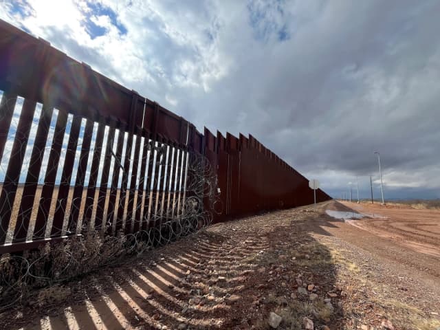 Una valla de seguridad de 5.5 metros de altura se fusiona con una valla de bolardos de acero de 9 metros construida durante el primer mandato del presidente Donald Trump en Douglas, Arizona, el 22 de enero de 2026. (Allan Stein/The Epoch Times)