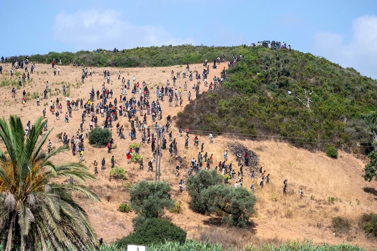 Los migrantes se reúnen en una colina mientras intentan cruzar desde la ciudad fronteriza de Fnideq, en Marruecos, hacia el enclave español de Ceuta el 15 de agosto de 2026. (Foto AP)