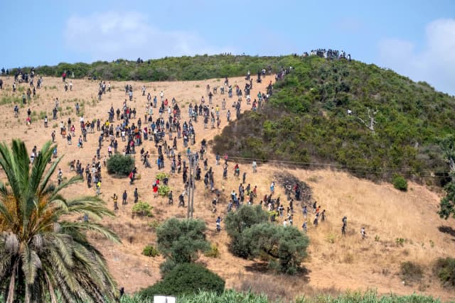 Los migrantes se reúnen en una colina mientras intentan cruzar desde la ciudad fronteriza de Fnideq, en Marruecos, hacia el enclave español de Ceuta el 15 de agosto de 2026. (Foto AP)