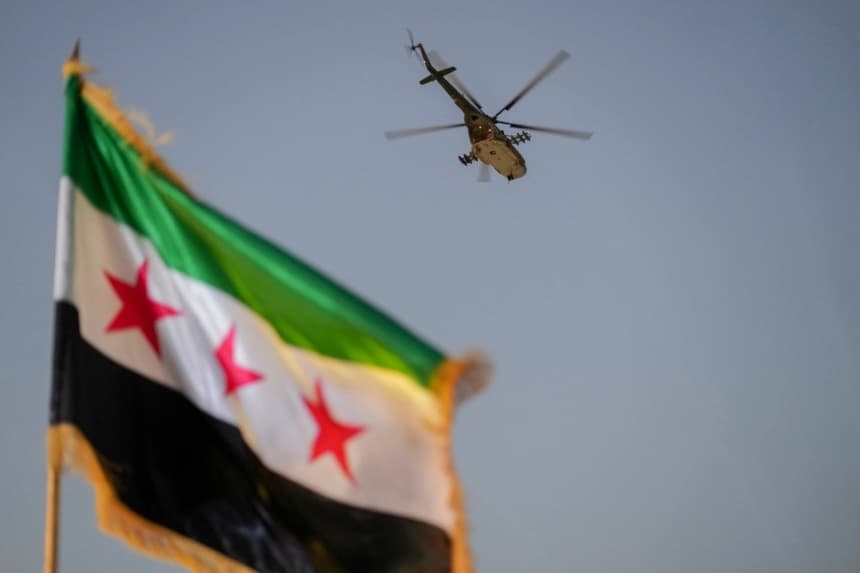 Un helicóptero militar sobrevuela una bandera siria en Damasco, Siria, el 9 de agosto de 2026. (Omar Albam/Middle East Images vía AFP/Getty Images)