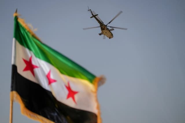 Un helicóptero militar sobrevuela una bandera siria en Damasco, Siria, el 9 de agosto de 2026. (Omar Albam/Middle East Images vía AFP/Getty Images)