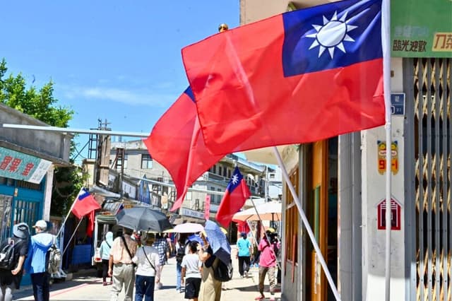 Banderas taiwanesas ondeando en un carril de una calle mientras turistas pasean por las islas Kinmen de Taiwán, el 11 de agosto de 2022. (Sam Yeh/AFP vía Getty Images).