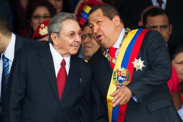 El presidente venezolano Hugo Chávez (a la derecha) conversa con su homólogo cubano Raúl Castro durante un desfile militar para conmemorar el vigésimo aniversario de su fallido intento de golpe de Estado, el 4 de febrero de 2012, en Caracas.(JUAN BARRETO/AFP vía Getty Images)