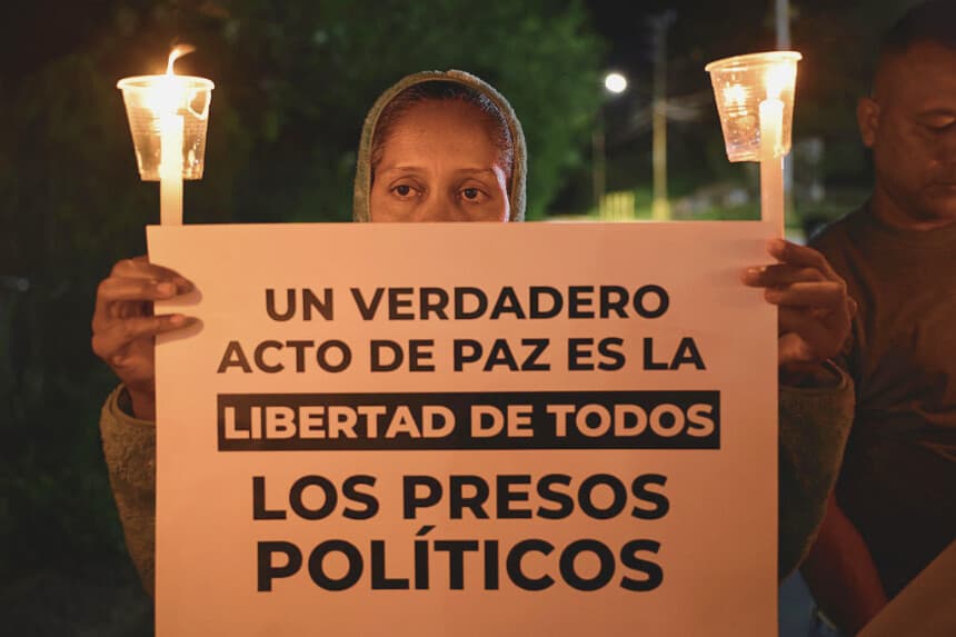Un familiar de los presos sostiene velas y un letrero el 9 de enero de 2026 en Miranda, Venezuela. (Jesús Vargas/Getty Images)