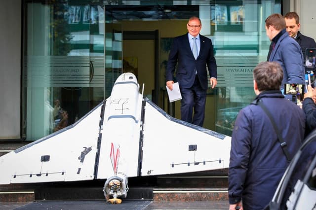 Oleg Ozerov (C), embajador de Rusia en Chisinau, observa un dron Gerbera de fabricación rusa recuperado por la policía moldava el 25 de noviembre de 2025 y expuesto en las escaleras de la entrada del Ministerio de Relaciones Exteriores (MAEIE) de Moldavia en Chisinau el 26 de noviembre de 2025. (Elena Covalenco/AFP vía Getty Images).