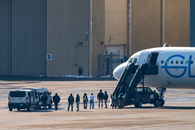 Agentes del ICE observan mientras los detenidos suben a un avión en el Aeropuerto Internacional de Minneapolis-St. Paul el 24 de febrero de 2026. (Stephen Maturen/Getty Images)