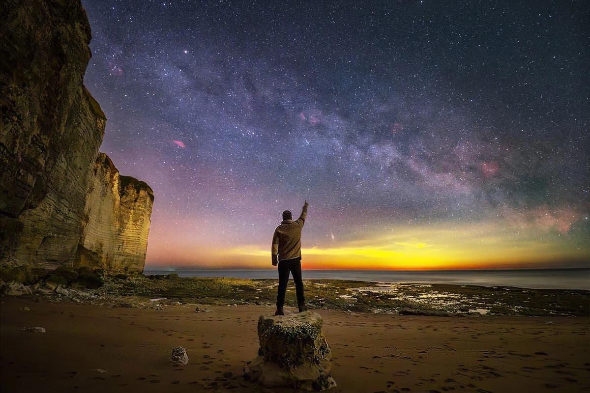 Un hombre posa en la orilla bajo una panorámica de la Vía Láctea. (Cortesía de Evgeni Tcherkasski).