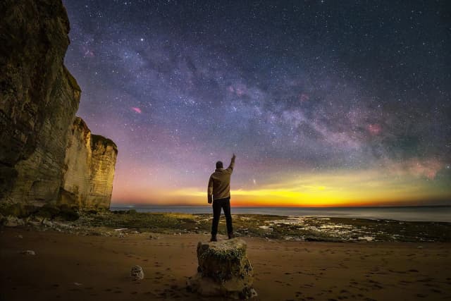 Un hombre posa en la orilla bajo una panorámica de la Vía Láctea. (Cortesía de Evgeni Tcherkasski).
