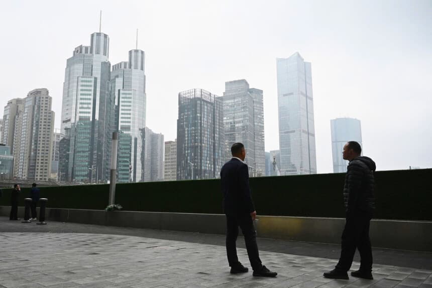 Dos hombres charlan frente a edificios de oficinas en el distrito central de negocios de Beijing el 4 de marzo de 2026. (Greg Baker/AFP vía Getty Images).
