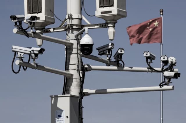 Una bandera nacional china ondea cerca de las cámaras de vigilancia instaladas en una farola en la plaza de Tiananmen, en Pekín, el 15 de marzo de 2019. (Andy Wong/AP).