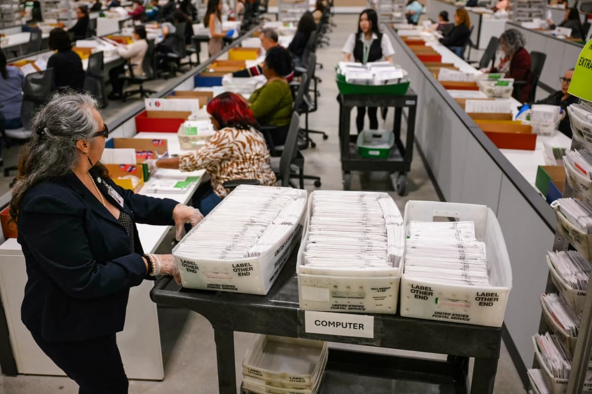Un funcionario electoral traslada las papeletas de voto por correo para su posterior recuento en el Centro de Procesamiento de Votos del Condado de Los Ángeles durante las elecciones primarias estatales de California en City of Industry, California, el 2 de junio de 2026. (Patrick T. Fallon / AFP vía Getty Images).