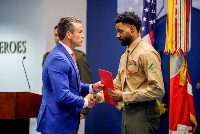 El secretario de Guerra, Pete Hegseth (izquierda), le da la mano al teniente coronel de la Infantería de Marina Jordan Houston (derecha) durante un evento para honrar a los marines que prestaban servicio durante el atentado con bomba de Abbey Gate de 2021, en el Pentágono, en Arlington, Virginia, el 26 de agosto de 2026. A tres marines estadounidenses de la Compañía Golf se les elevó formalmente el nivel de sus condecoraciones al valor para honrar su heroísmo y sus acciones que salvaron vidas durante el atentado de Abbey Gate de 2021, en el Aeropuerto Internacional Hamid Karzai de Kabul. (Andrew Harnik/Getty Images)