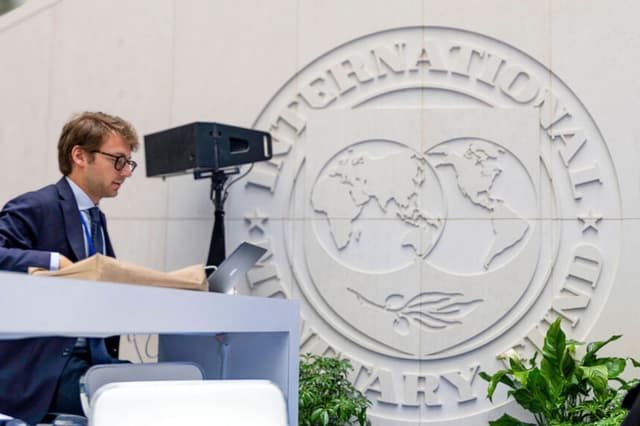 Una persona trabaja en su computadora portátil en el atrio del edificio del Fondo Monetario Internacional (FMI) en Washington, D.C., el 13 de abril de 2026. (Kent Nishimura / AFP vía Getty Images)