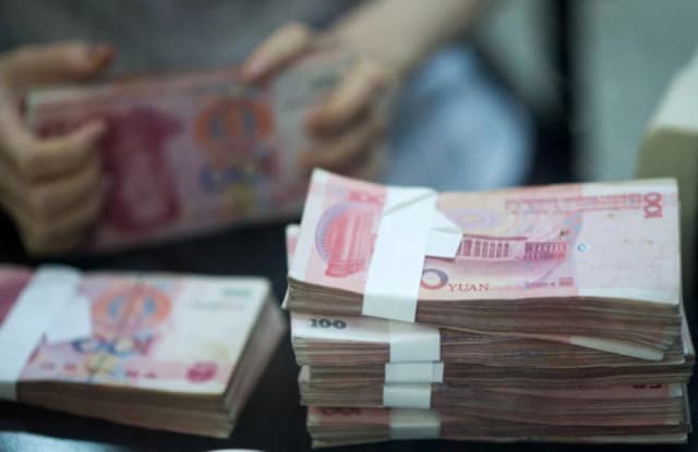 Una trabajadora en una sucursal bancaria cuenta dinero mientras atiende a un cliente en la zona piloto de libre comercio de China (Shanghái) durante un recorrido para medios el 24 de septiembre de 2014. (Johannes Eisele/AFP vía Getty Images)