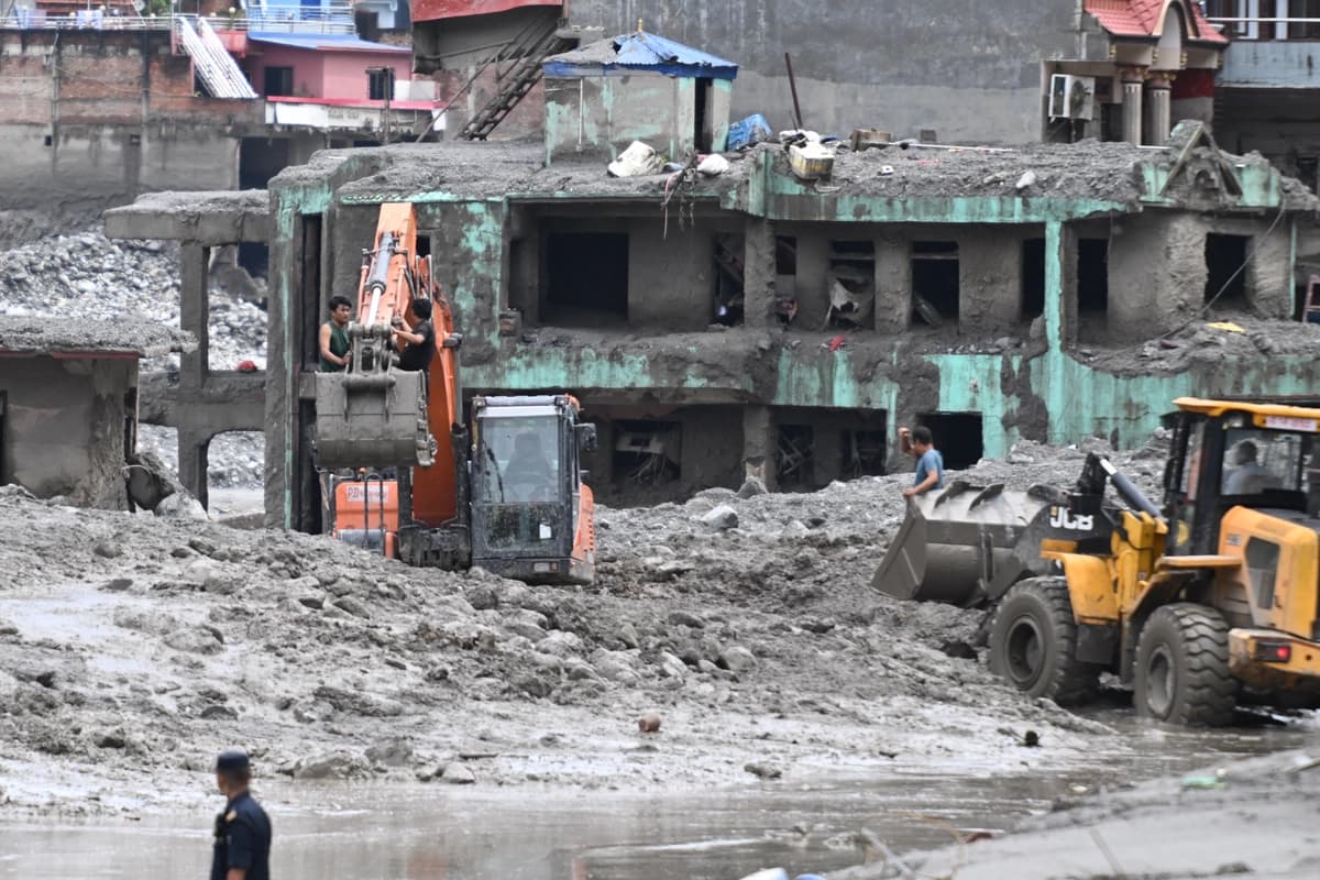 Una excavadora (izquierda) ayuda a las personas a recoger algunas de sus pertenencias de sus casas tras las inundaciones repentinas en Trishuli, en el distrito de Nuwakot, Nepal, el 29 de agosto de 2026. (Arun Sankar/AFP vía Getty Images)