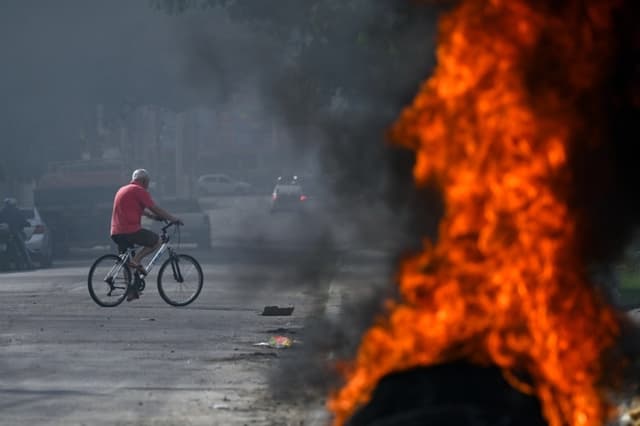 Un hombre pasa en bicicleta junto a llantas en llamas durante una operación contra el tráfico de drogas en la favela Cidade Alta, parte del Complejo Israel, en Río de Janeiro, Brasil, el 10 de junio de 2025. (Mauro Pimentel/AFP vía Getty Images)