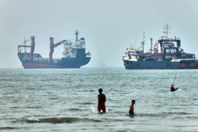 Varias personas se adentran en el agua con buques de carga anclados al fondo, en el estrecho de Ormuz, frente a Bandar Abbas, Irán, el 30 de junio de 2026. (Amirhosein Khorgooi/ISNA vía AP).