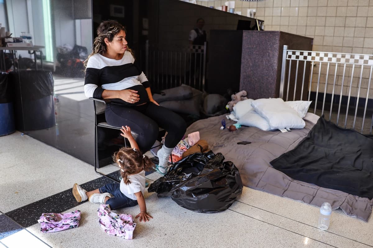 Una madre migrante con siete meses de embarazo se sienta en el vestíbulo de una comisaría donde ella y otros migrantes se han alojado desde su llegada a la ciudad, en Chicago, el 9 de mayo de 2023. (Scott Olson/Getty Images).