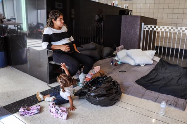 Una madre migrante con siete meses de embarazo se sienta en el vestíbulo de una comisaría donde ella y otros migrantes se han alojado desde su llegada a la ciudad, en Chicago, el 9 de mayo de 2023. (Scott Olson/Getty Images).