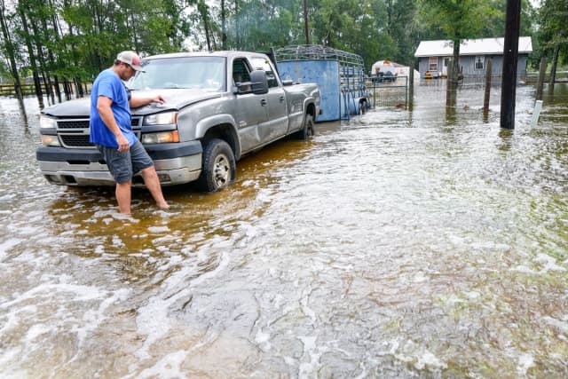 Chase Barfield camina hacia su camioneta mientras saca sus pertenencias y a sus perros de las inundaciones que rodean su casa tras el paso de la tormenta tropical Edouard cerca de Honey Island, Texas, el 2 de septiembre de 2026. (Brett Coomer/Houston Chronicle vía AP)