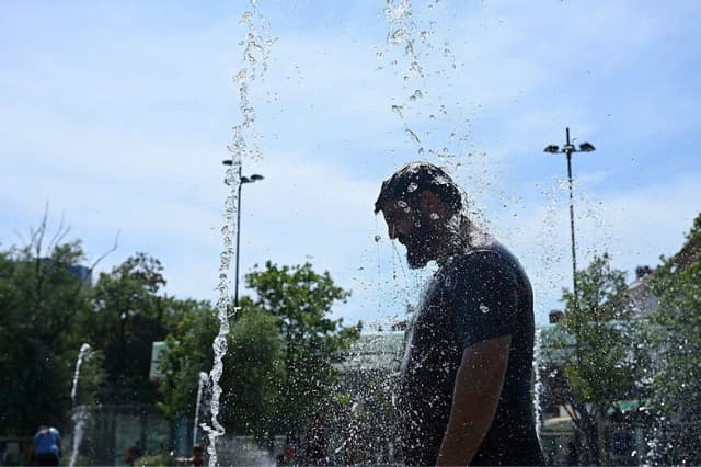 Un hombre se enfría en rociados de agua durante una ola de calor en Bruselas el 25 de junio de 2026. (Nicolas Tucat/AFP vía Getty Images).